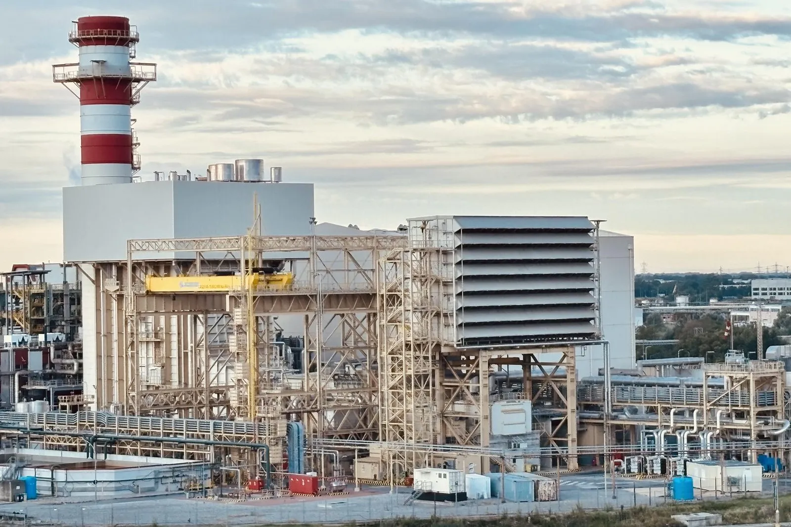 Central industrial con chimenea, estructura metálica y tuberías, vista desde el muelle